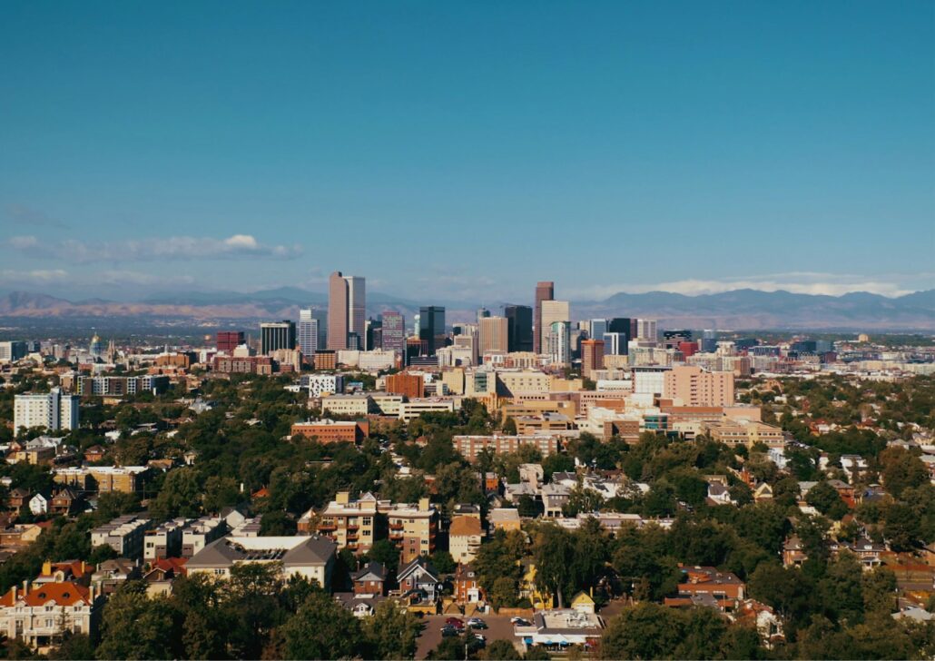 Denver skyline with Rocky Mountains in the background, showcasing urban development and greenery, relevant to senior care services and active aging in Denver, CO.