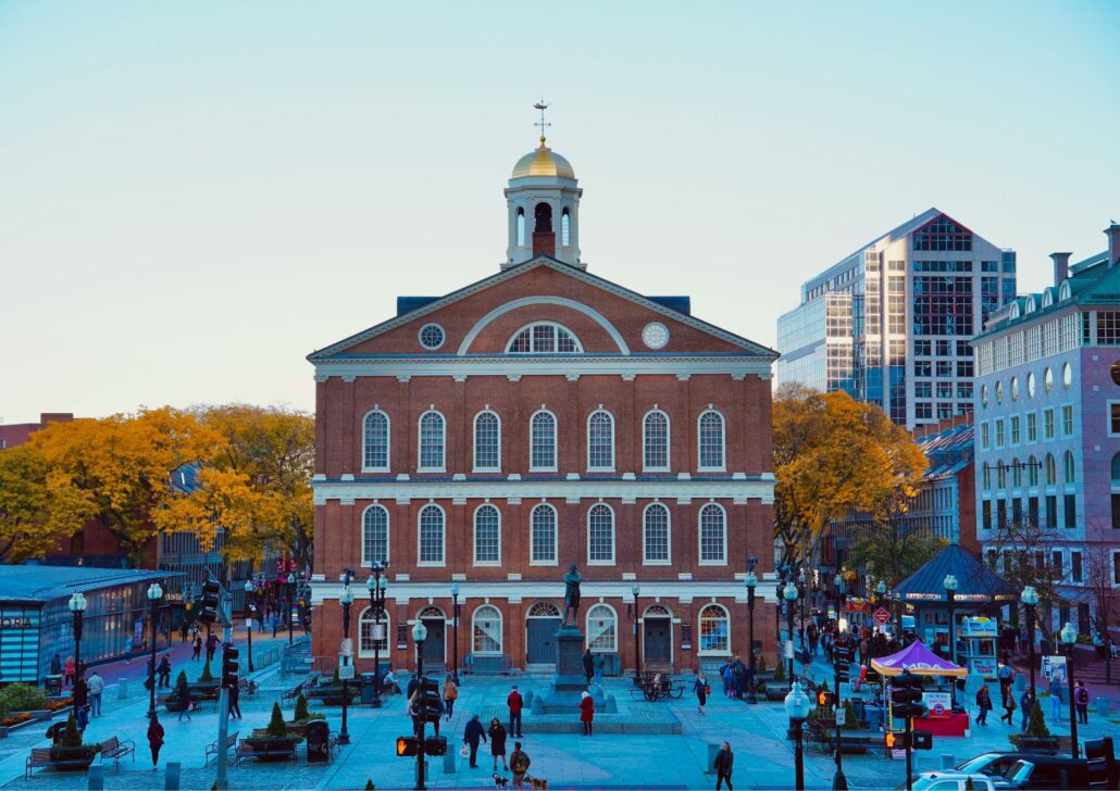 Historic Faneuil Hall in Boston, surrounded by pedestrians and autumn foliage, symbolizing the city's active community and cultural heritage.