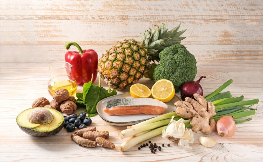 Colorful assortment of anti-inflammatory foods including salmon, broccoli, avocados, blueberries, walnuts, ginger, and fresh vegetables, emphasizing nutritious meal planning for seniors.