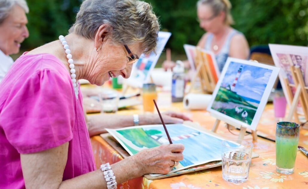 Senior woman smiling while drawing with the group