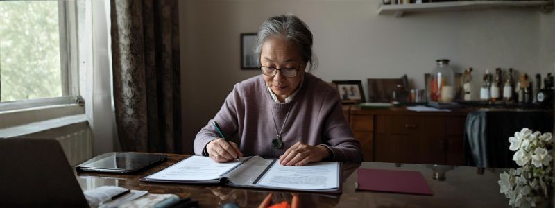 female senior writing on legal documents